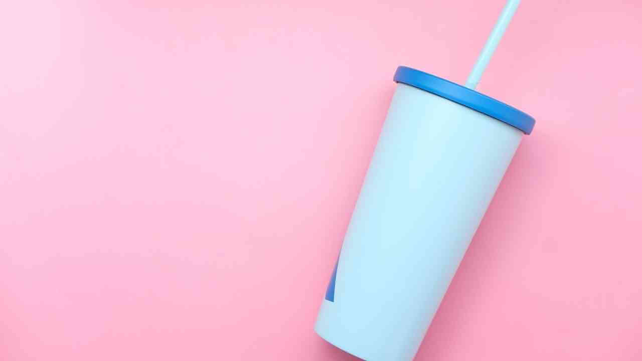 a cup with a straw on a pink background