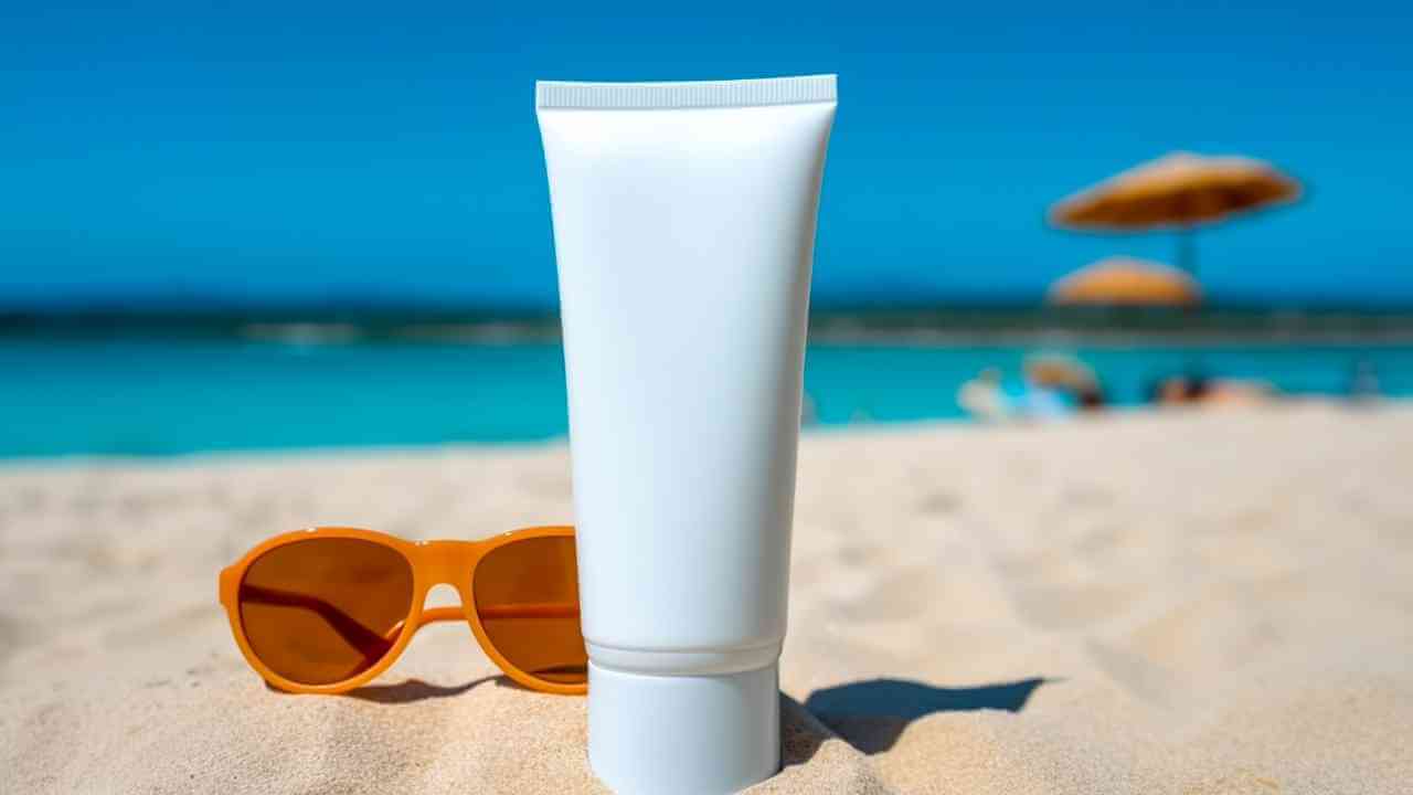 a tube of sunscreen cream and sunglasses on the beach