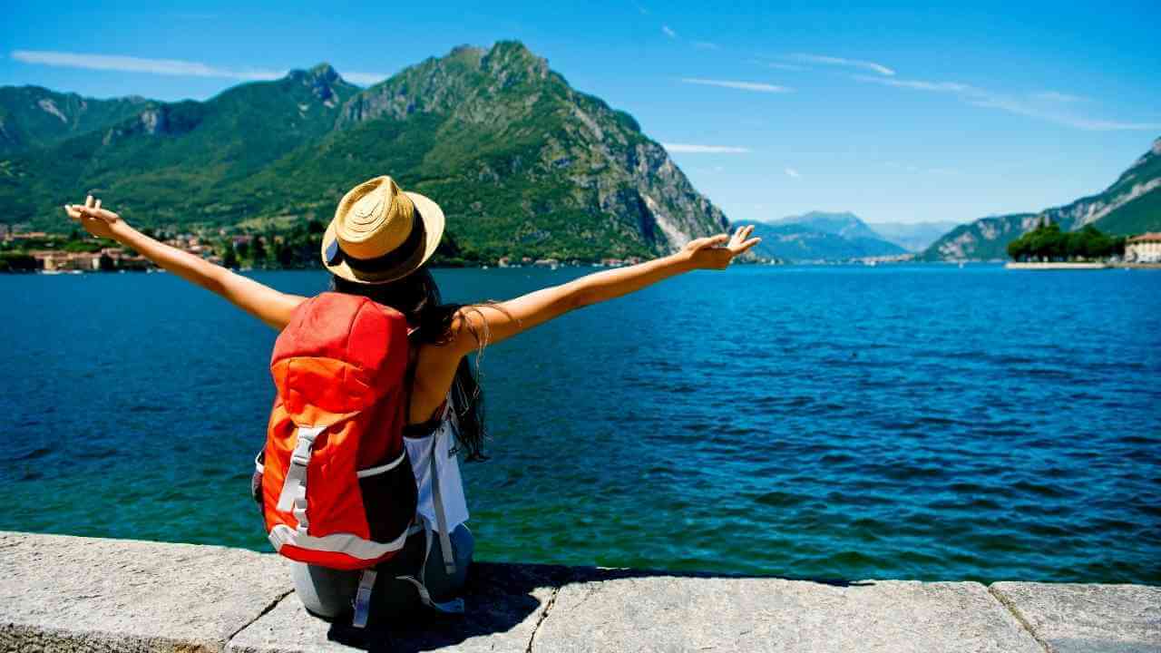 a person with their arms outstretched looking at the lake and mountains