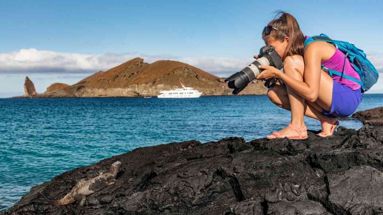 a person taking a photo of the ocean with a boat in the background