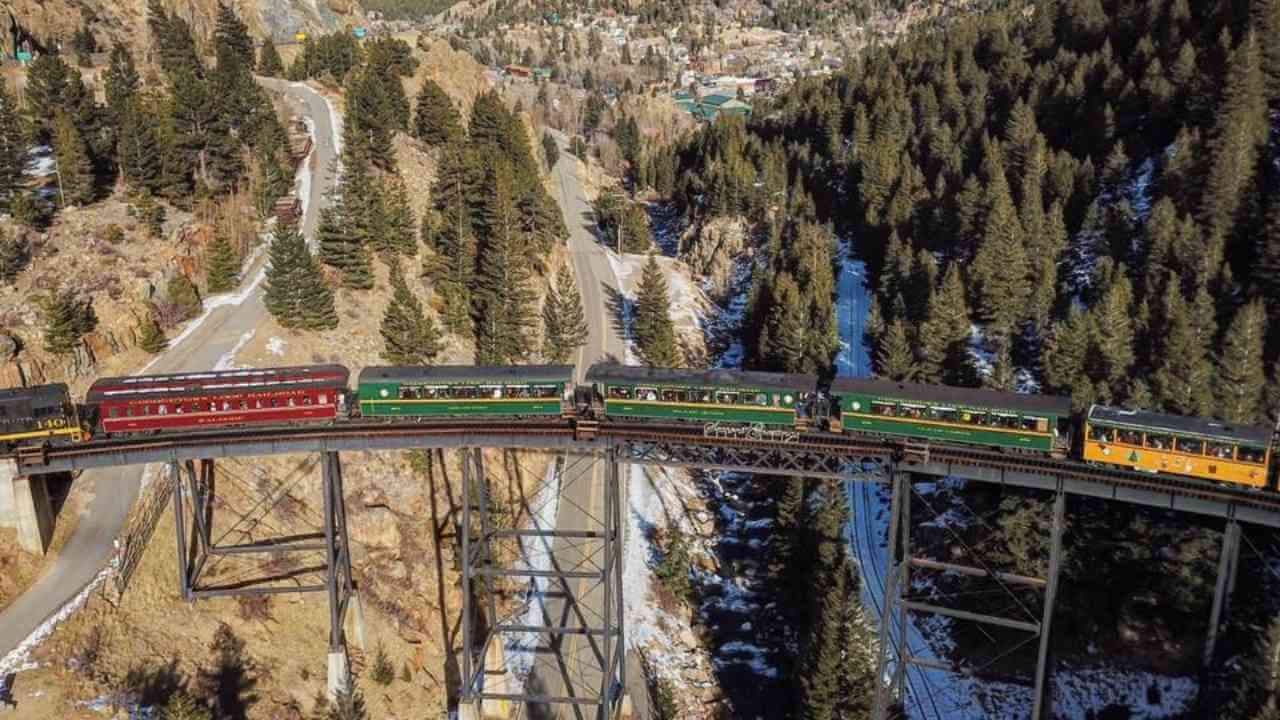 an aerial view of a train traveling over a bridge