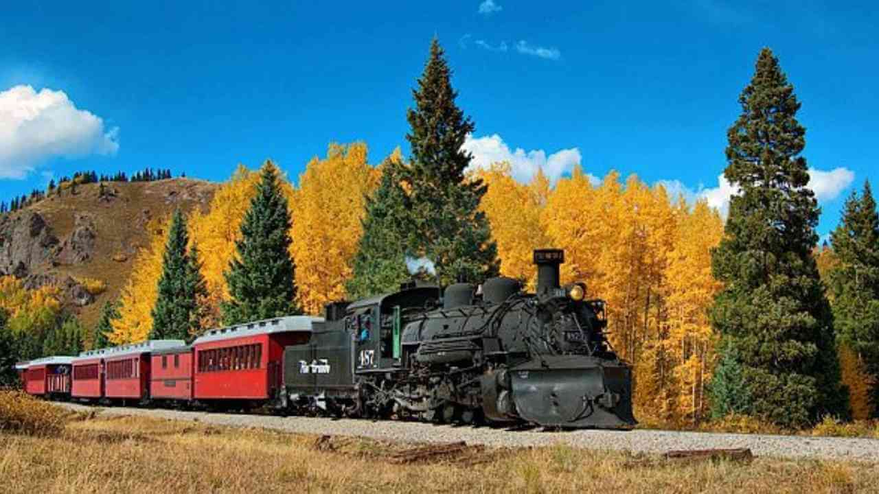 a red and black train traveling through the mountains