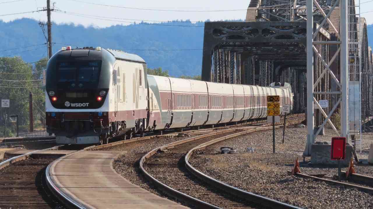 a train on the tracks with a bridge in the background