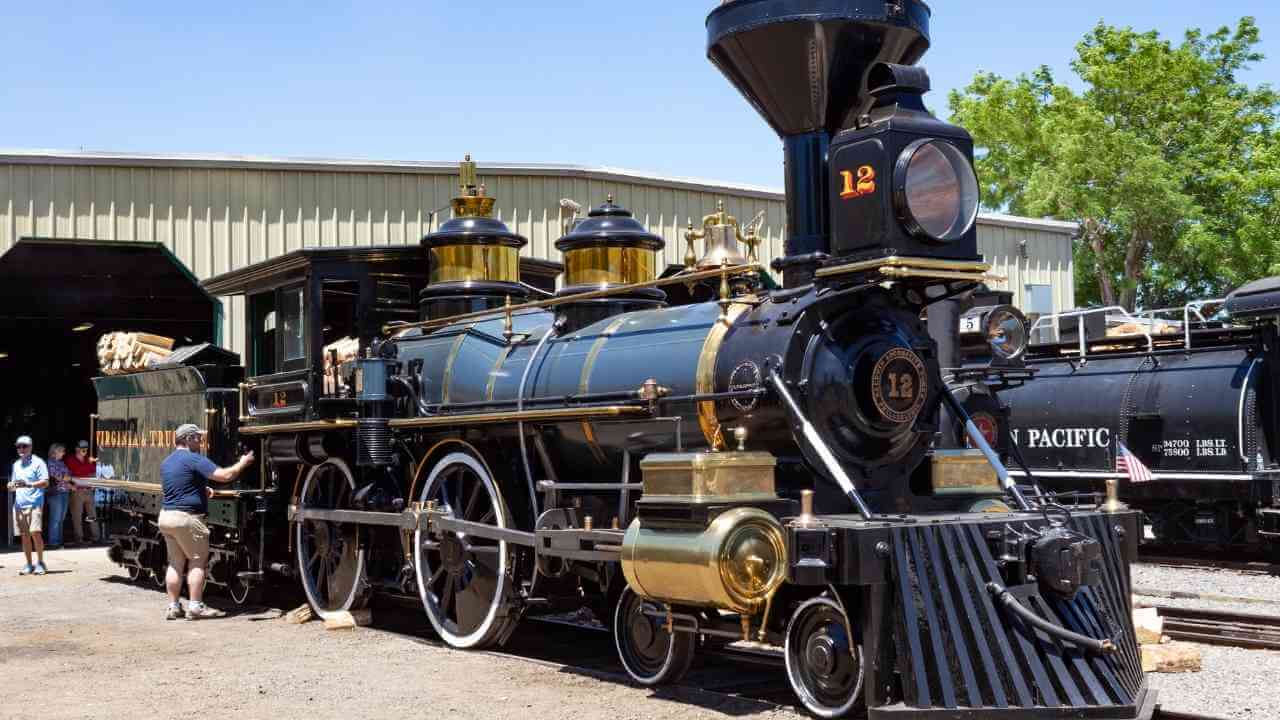 an old fashioned steam locomotive is parked in front of a building