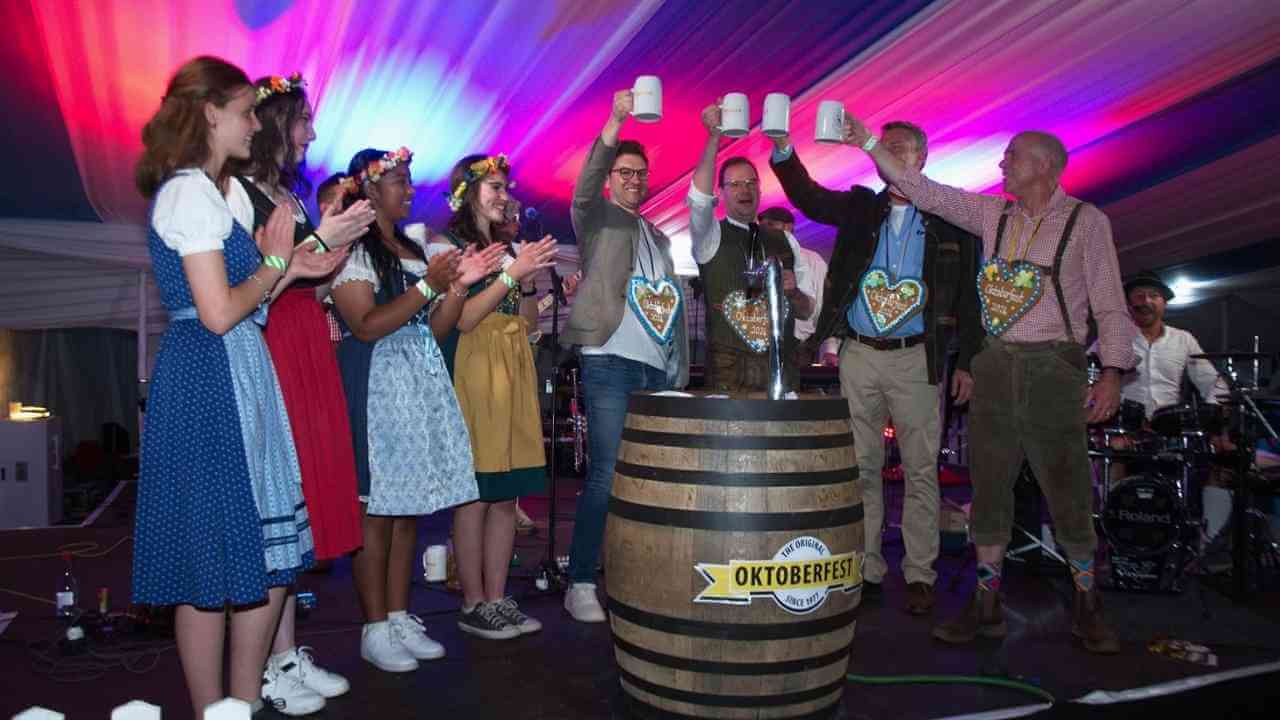 a group of people standing around a barrel of beer