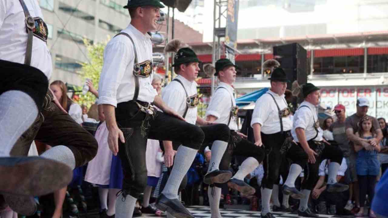 a group of people in traditional bavarian clothing dancing on a street.