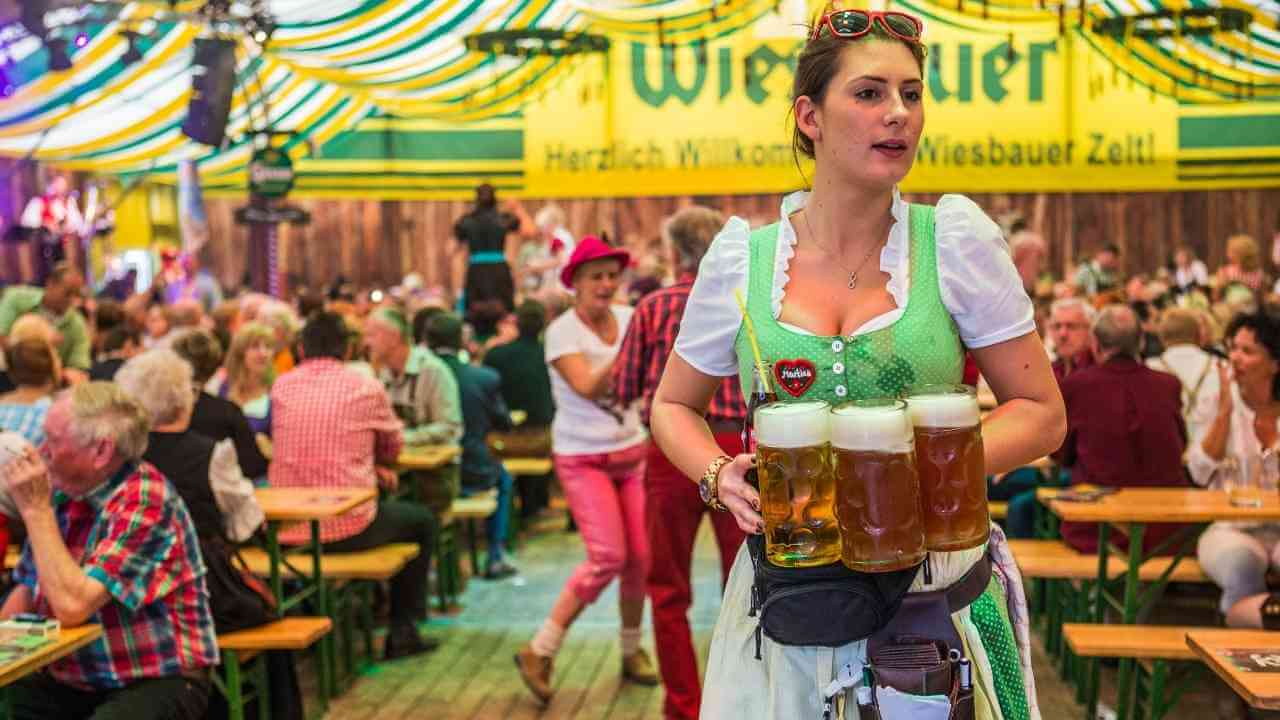 A person in an Oktoberfest costume holding a tray of beer