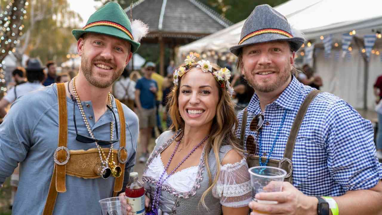 three people in bavarian costumes at an outdoor event