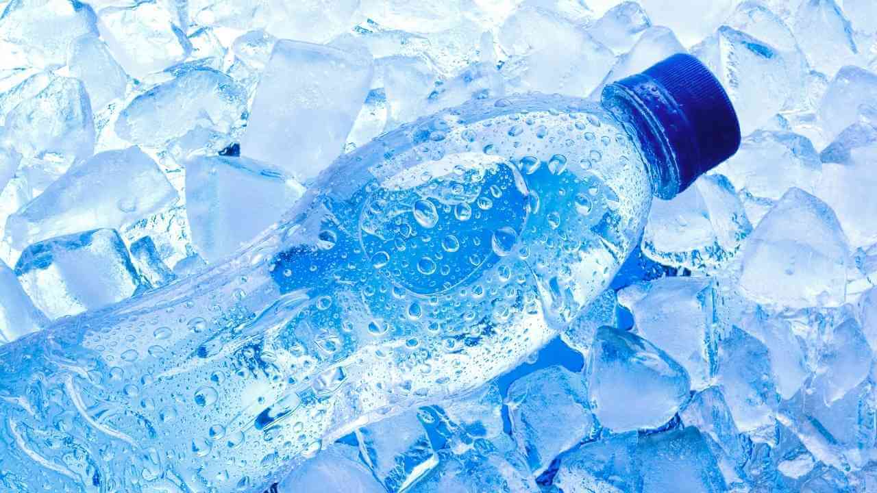 a bottle of water sitting on top of a pile of ice