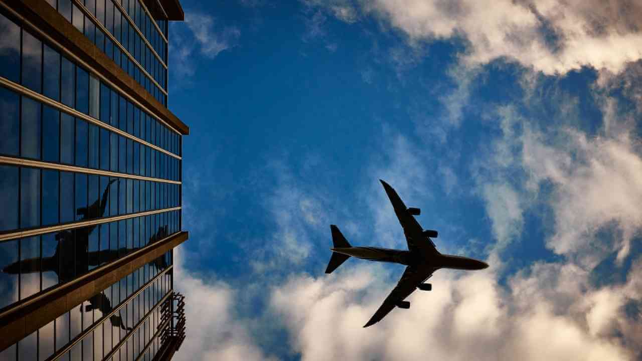 an airplane flying in front of a tall building