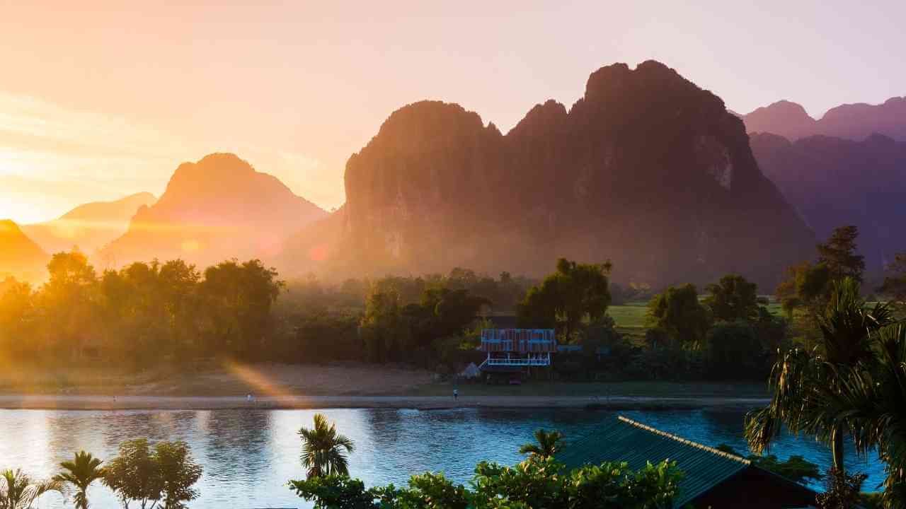 the sun rises over the mountains and river in laos