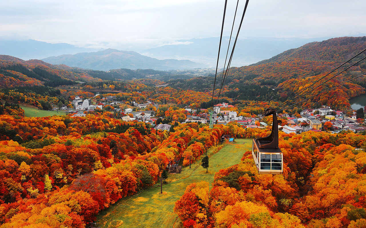 Aerial view of a scenic cable car flying over the beautiful autumn valley of Zao