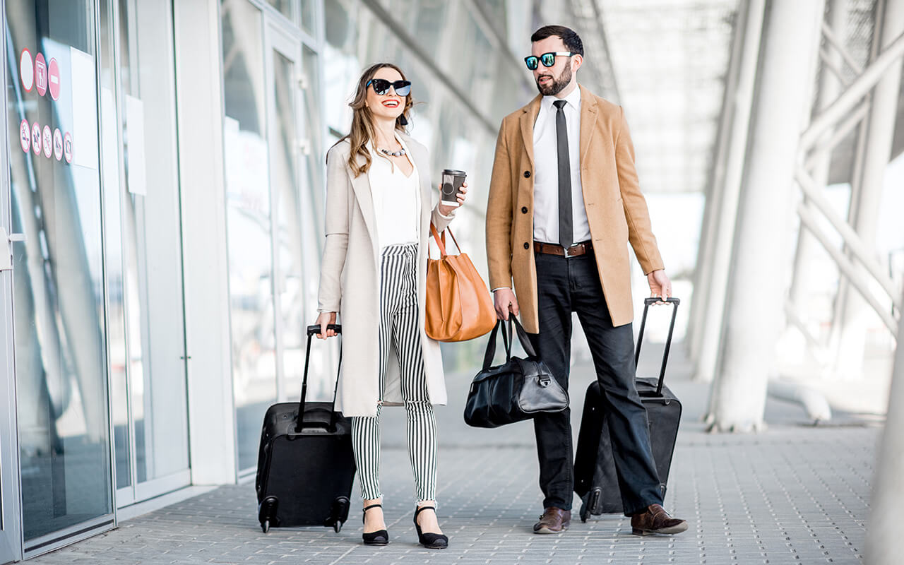 Stylishly dressed couple with bags at the airport