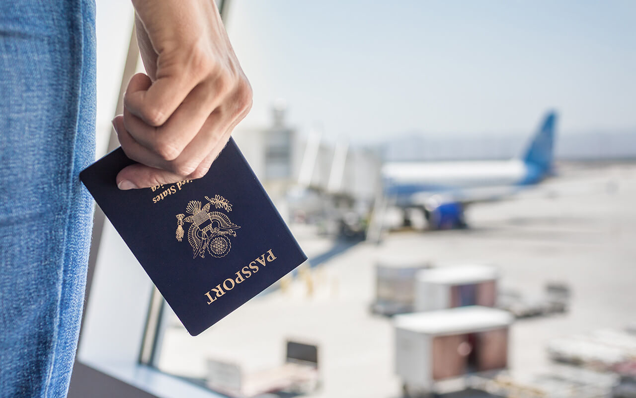 Hand holding USA passport at airport.