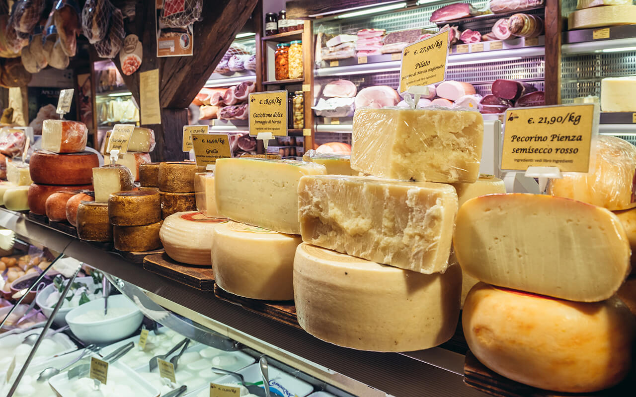 Interior of food store with cheese for sale on covered indoor food market Mercato di Mezzo in historic part of Bologna city, Italy