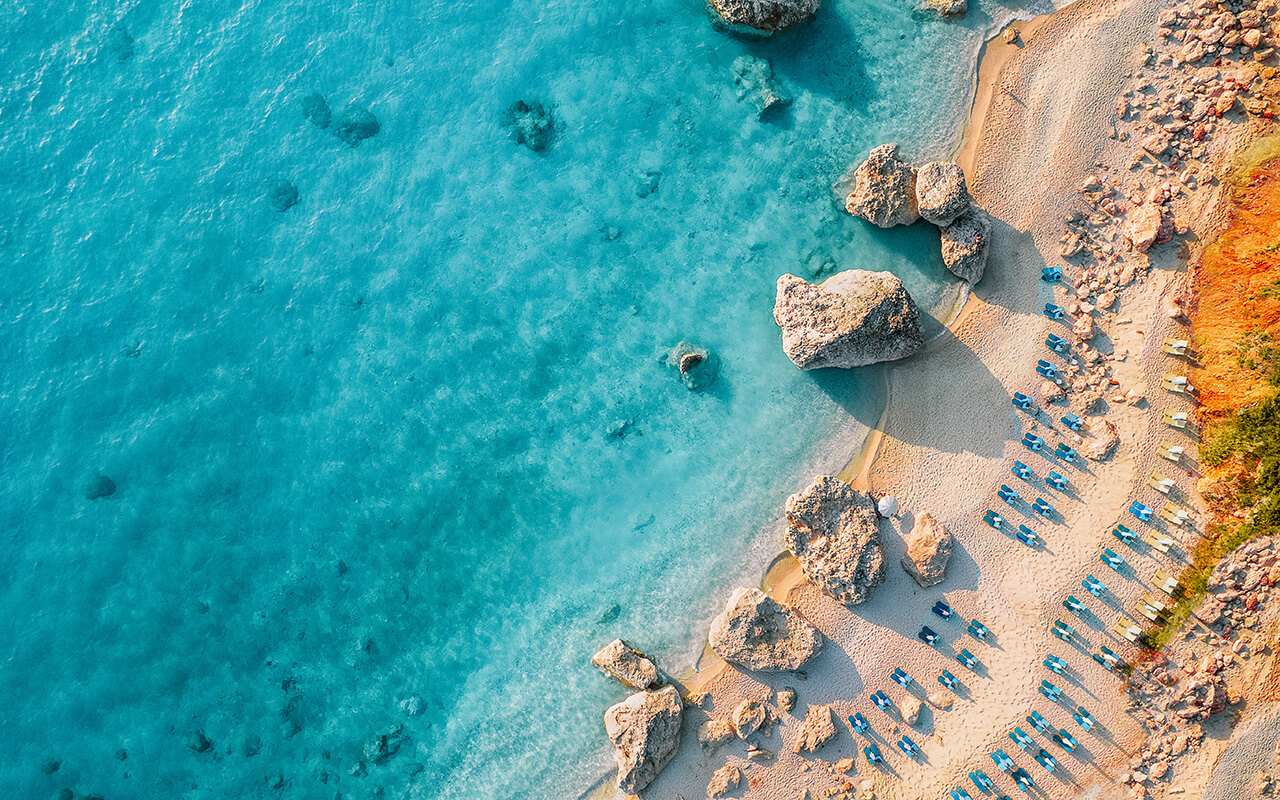 Top view of beach chairs by turquoise sea in Greece