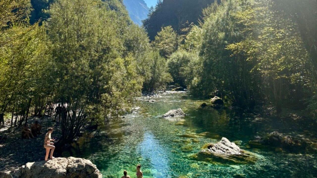 two people are standing on rocks in the middle of a river