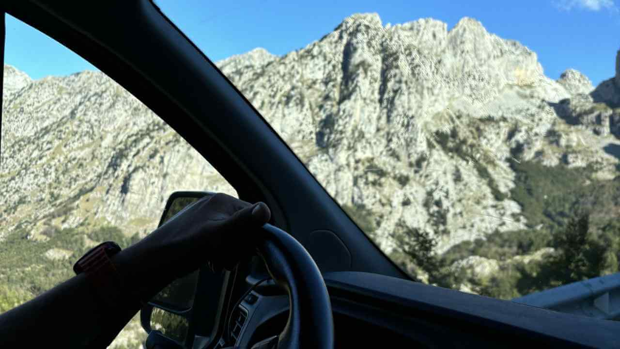 a person driving in a car with mountains in the background