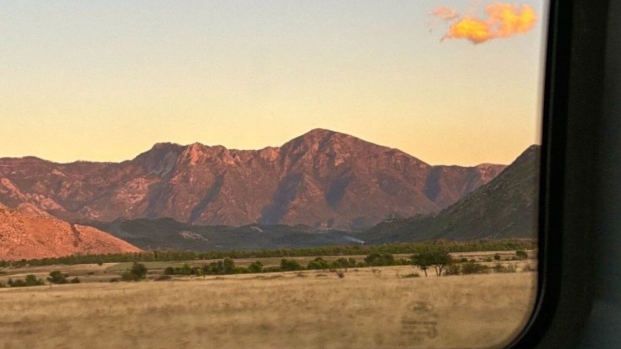 a view out the window of a train with mountains in the background