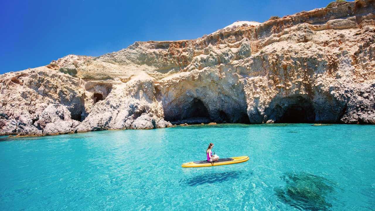 a person in a kayak in the clear blue water of a cave