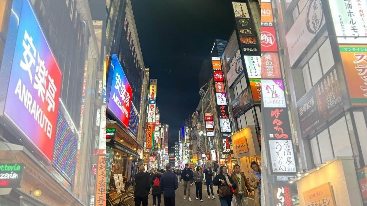 a busy city street at night with lots of neon signs