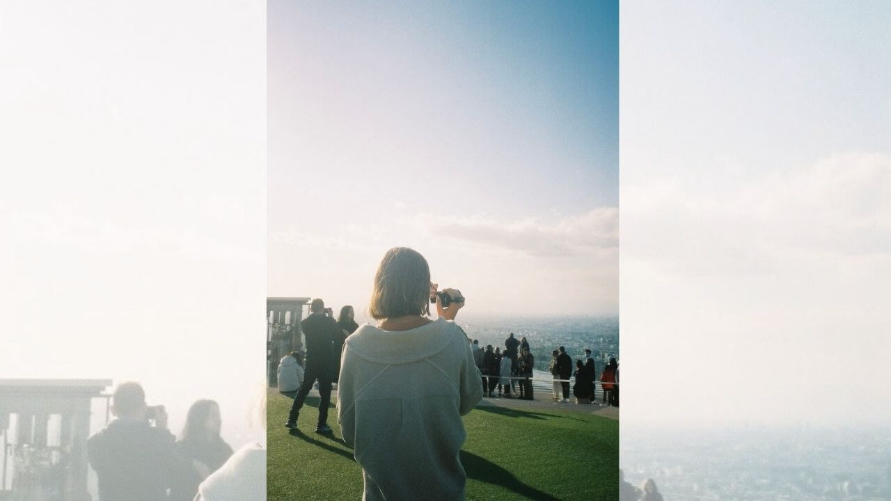 a person taking a picture of the city from the top of a hill