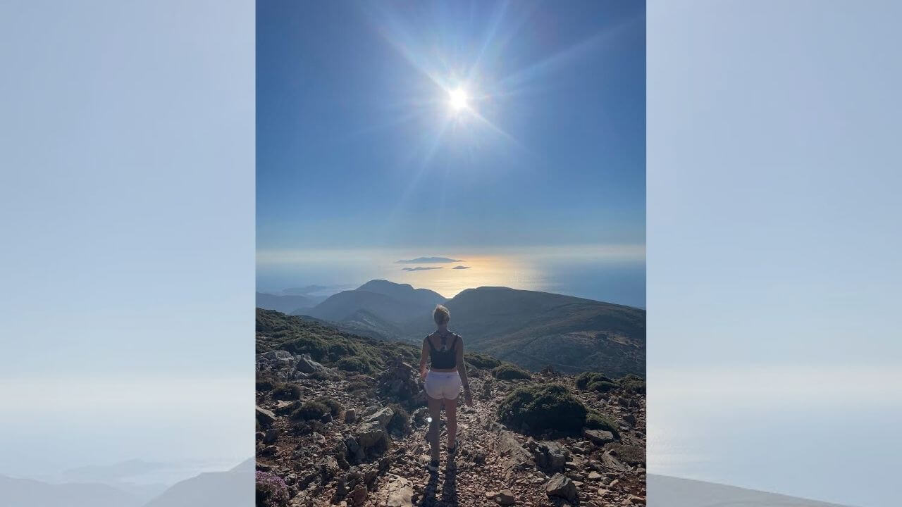 a person standing on the top of a mountain with the sun in the background