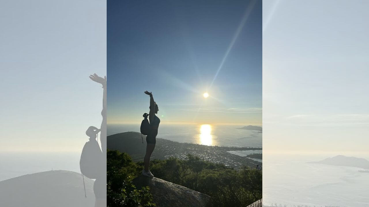 a person standing on top of a mountain with their arms up in the air