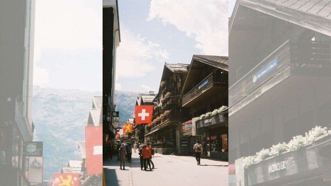 people walking down the street in front of a building with a swiss flag on it