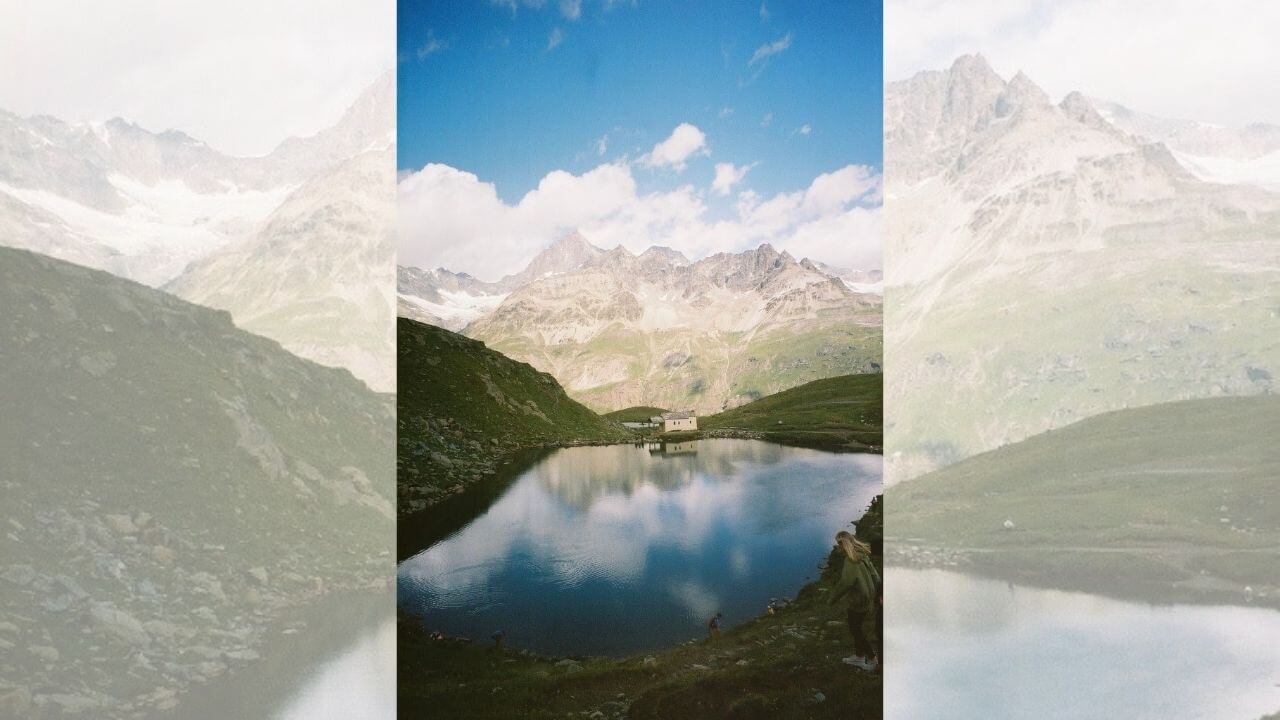 a person standing in front of a lake with mountains in the background