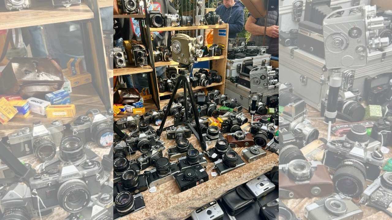 an assortment of old cameras on display at a flea market