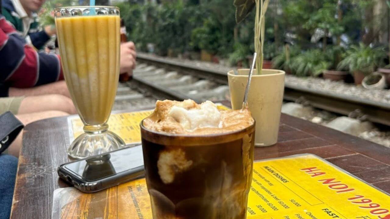 An iced coffee sitting on a table in front of a train