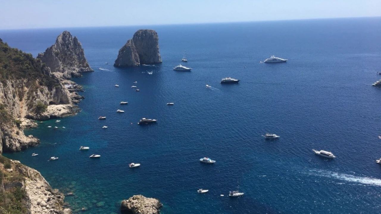 boats are anchored in the ocean near rocky cliffs