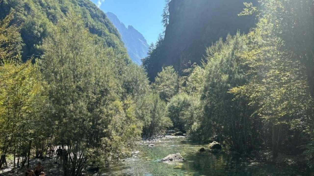 people walking along a river in the mountains