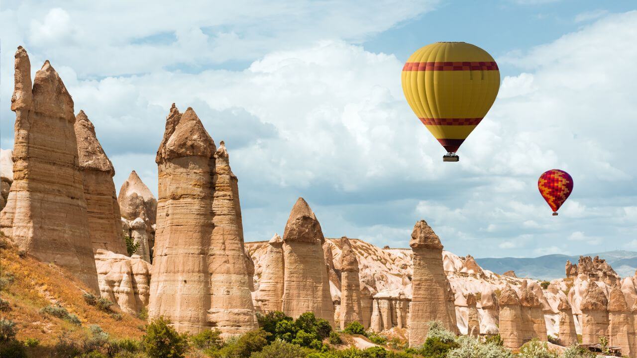 hot air balloons flying over rock formations in Cappadocia, Turkey