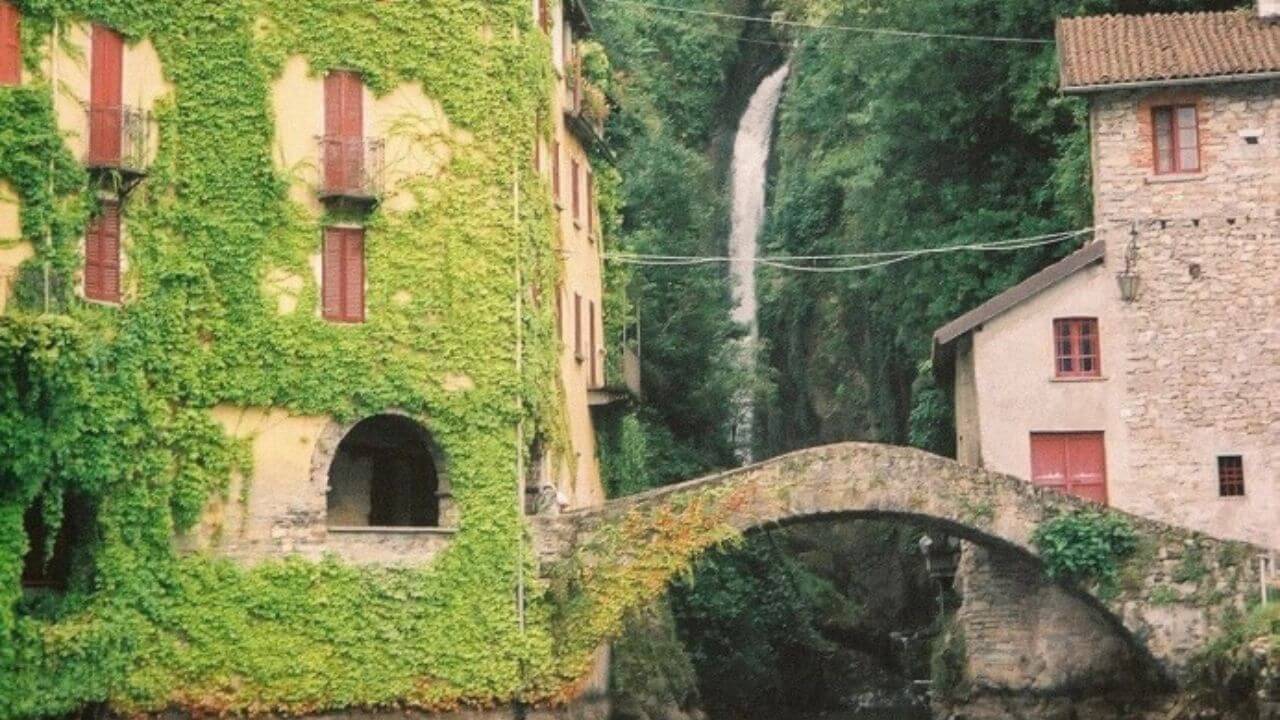 a bridge over a river with a waterfall in the background