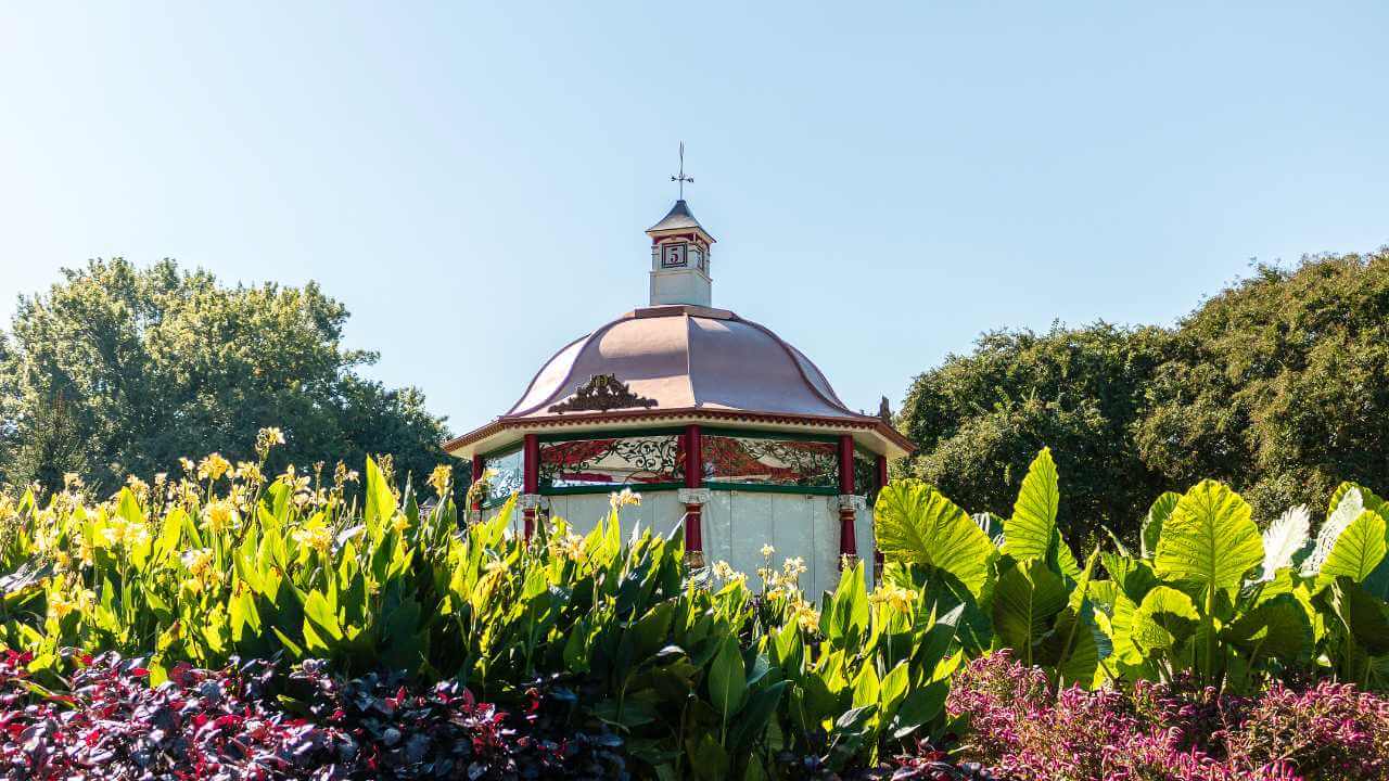 a gazebo in a park surrounded by lush green plants