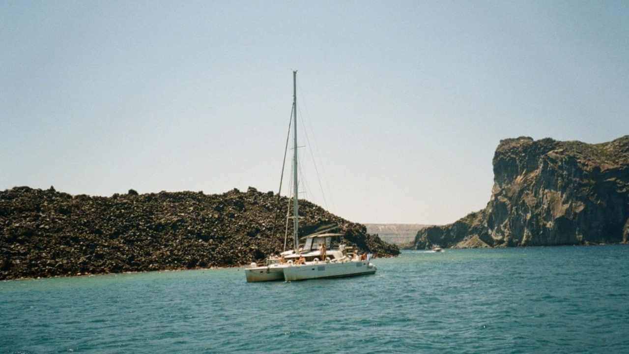 a catamaran in the water near a rocky island