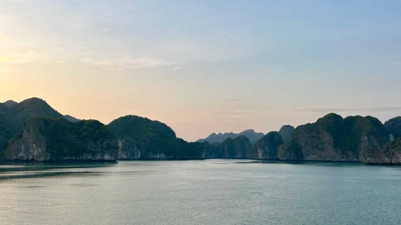 the sun is setting over a body of water with mountains in the background