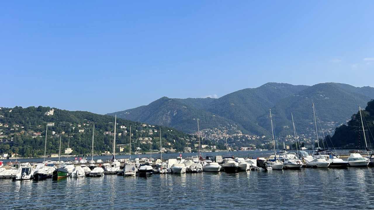 many boats are docked in the water in front of mountains