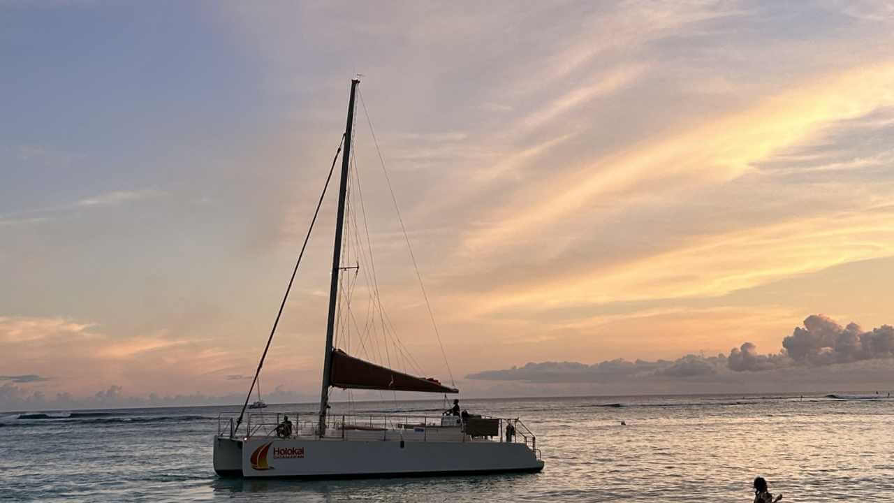 a sailboat is anchored in the ocean at sunset