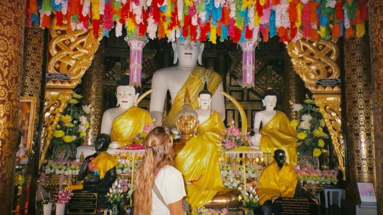 A person standing in front of a Buddhist shrine.