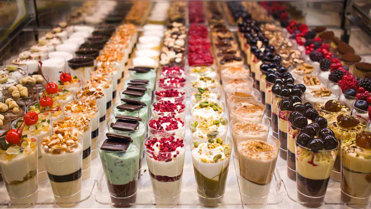 many different types of desserts are on display in a glass case