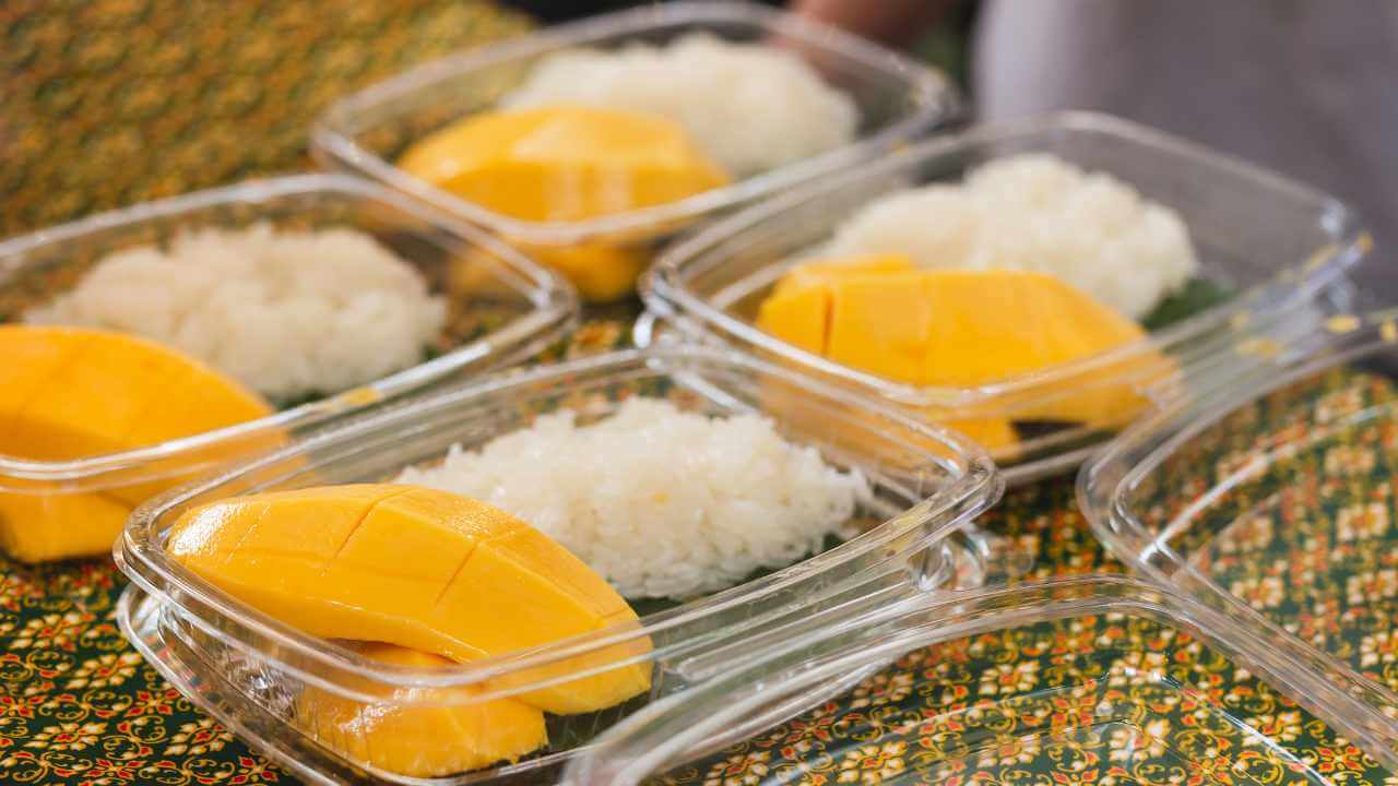 four plastic containers filled with rice and mangoes