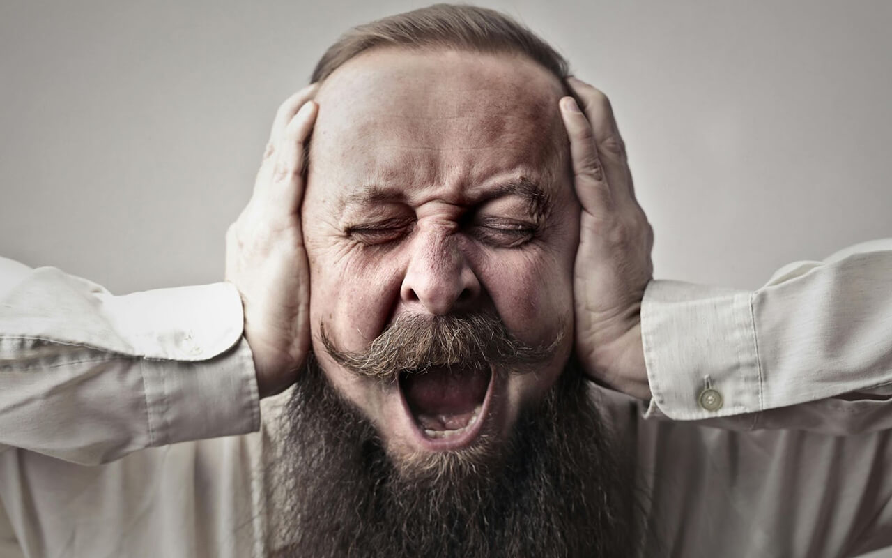 Man screaming and covering his ears