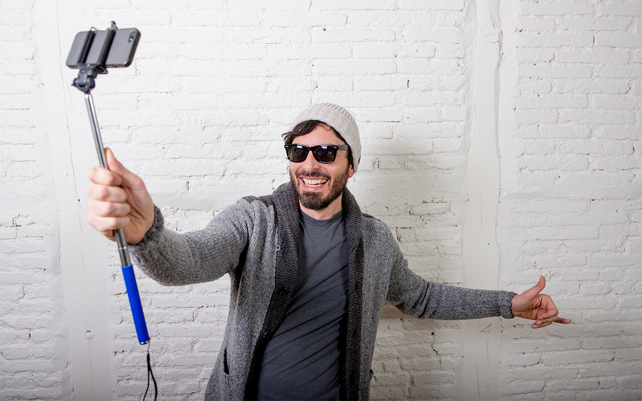 young hipster trendy blogger man holding stick recording selfie video in vlog concept