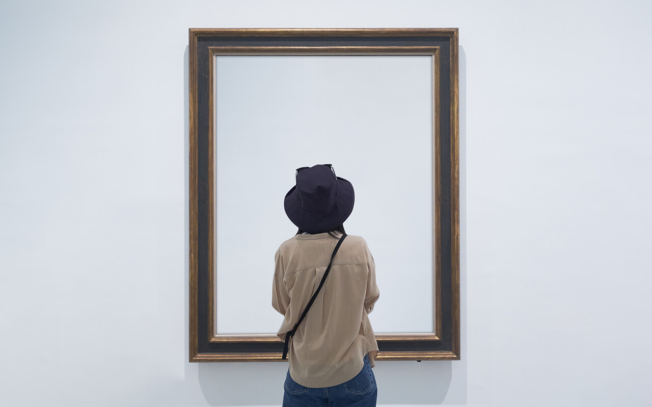 Person standing directly in front of a framed painting