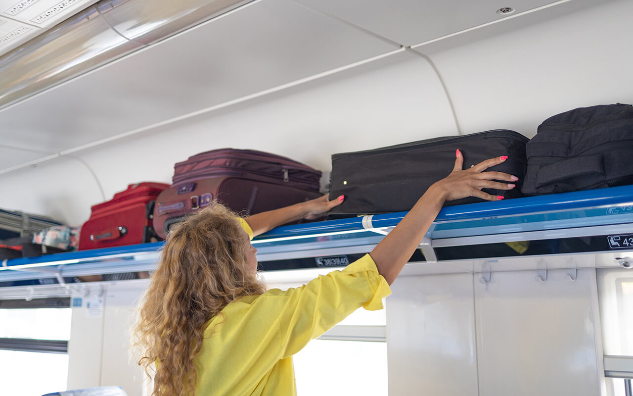 Woman stowing carry-on luggage on a plane