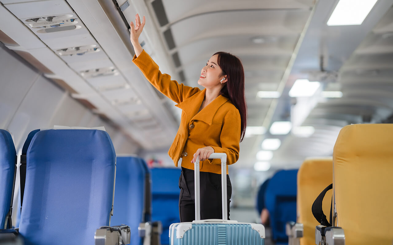 Woman loading her luggage into overhead bin