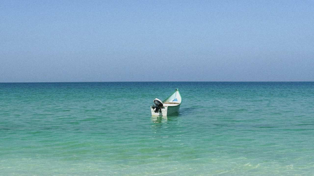 a small boat floating in the ocean near the shore